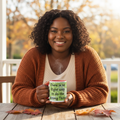 Lifestyle photo: a woman in a rust cardigan sipping from the Trademarked Quote mug with red interior on a fall porch table